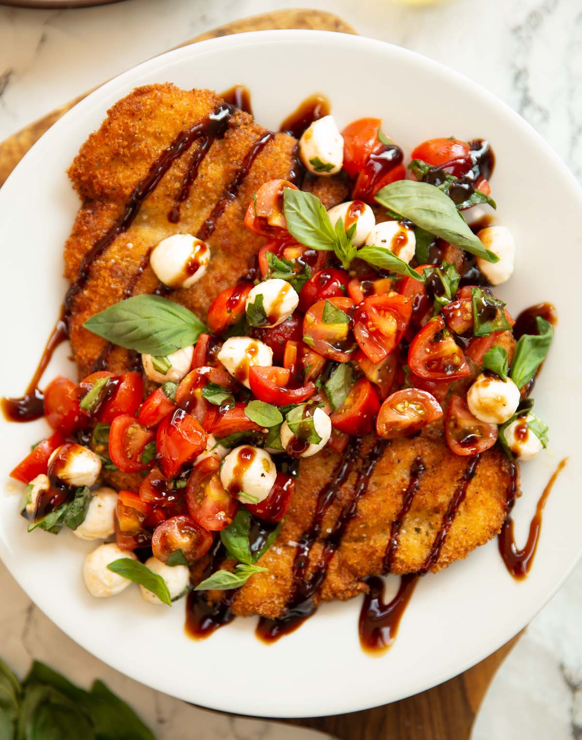 close up overhead shot of crispy caprese chicken on white plate