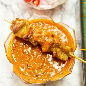 thai chicken skewer on glass pot of satay sauce