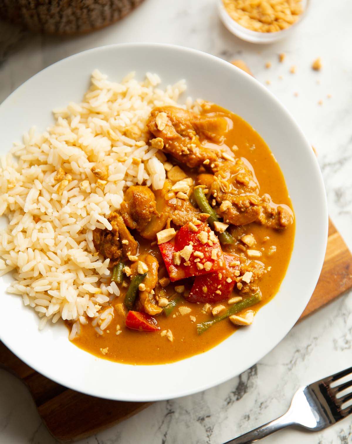 close up shot of slow cooker chicken satay in large white bowl with white rice