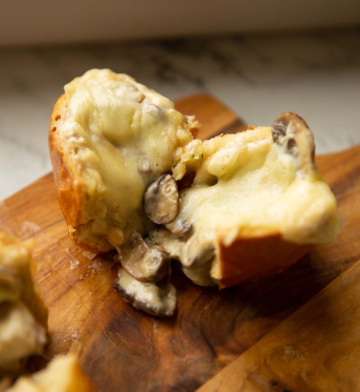 close up shot of chicken mushroom slider halved on wooden chopping board